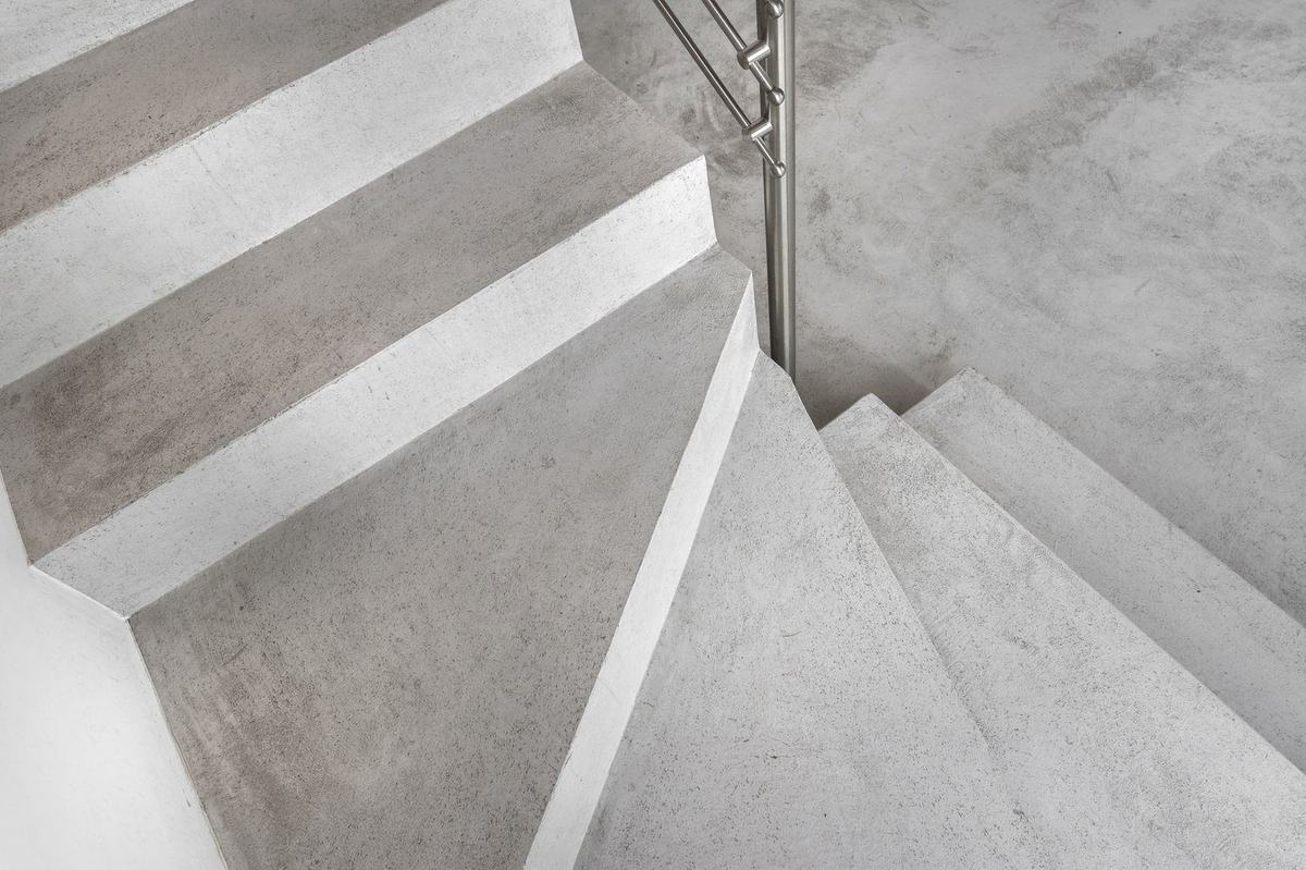 Betonowe schody w minimalistycznym domu oświetlone światłem z boku